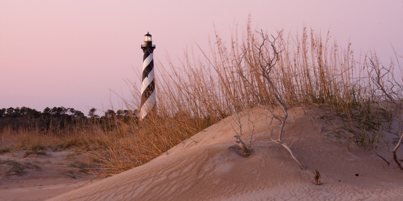Cape Hatteras Lighthouse Cape Hatteras Lighthouse in background behind small sand dune.