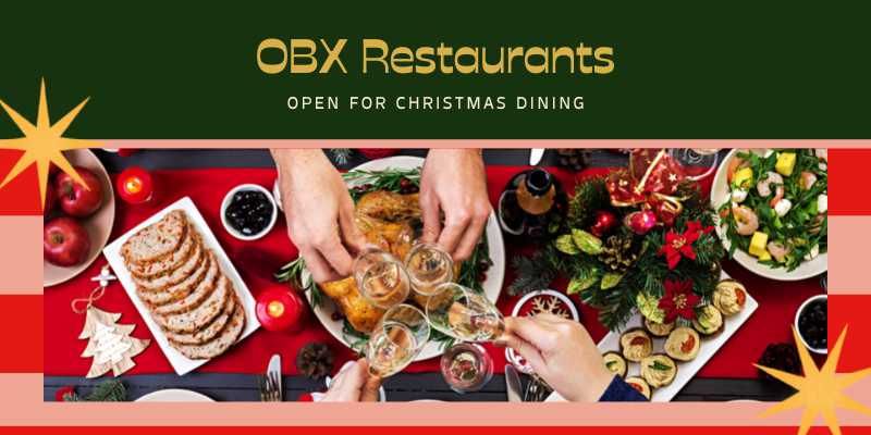 Image of table with red tablecloth and various foods for holiday dinner including turkey, salad, and champagne glasses.