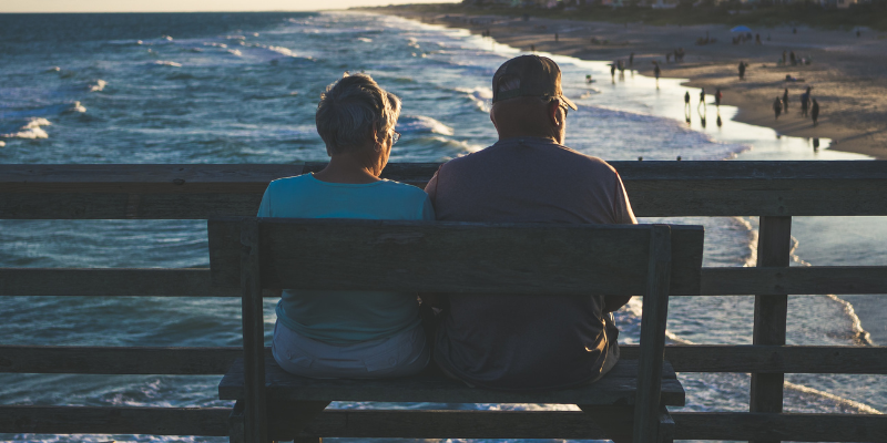 What is a snowbird? Image of a man and woman sitting together on a pier by the ocean.